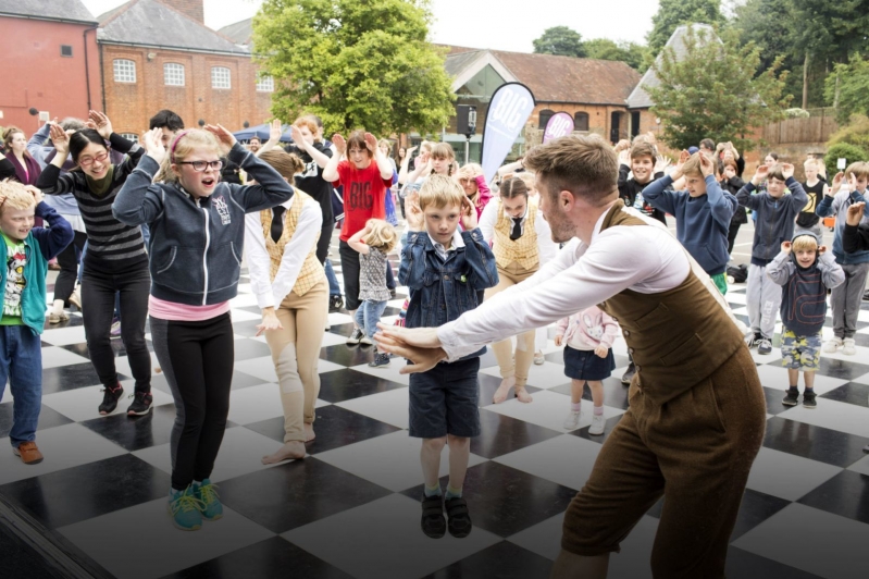 Male dancer guides large group of people on outdoor dance floor